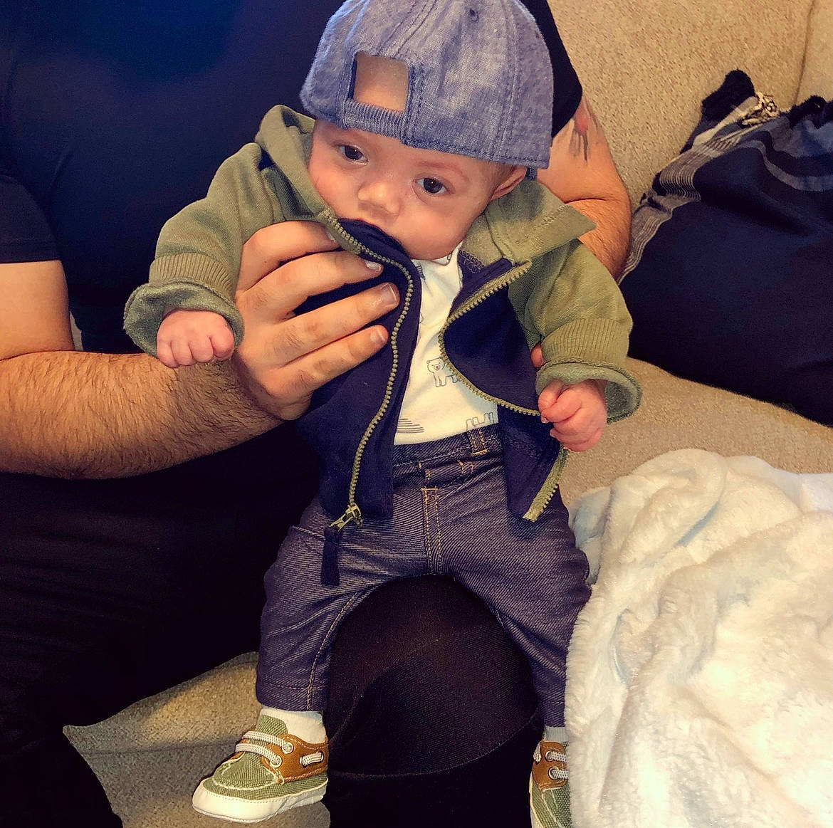 Jax is registered to the contest to win money with this photo: baby, baby_toddler_clothing, baseball_cap, cap, cheek, comfort, cool, eyebrow, face, finger, gesture, happy, head, headwear, human_body, lap, mouth, person, skin, sleeve
