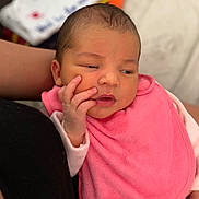 Anastasia participe au concours pour gagner de l'argent avec cette photo : baby, newborn, infant, pink_bib, hand, face, skin, clothing, person, portrait, resting, indoors, adult_arm, cute, small_hand, expression, young_child, soft_texture, warm, cozy
