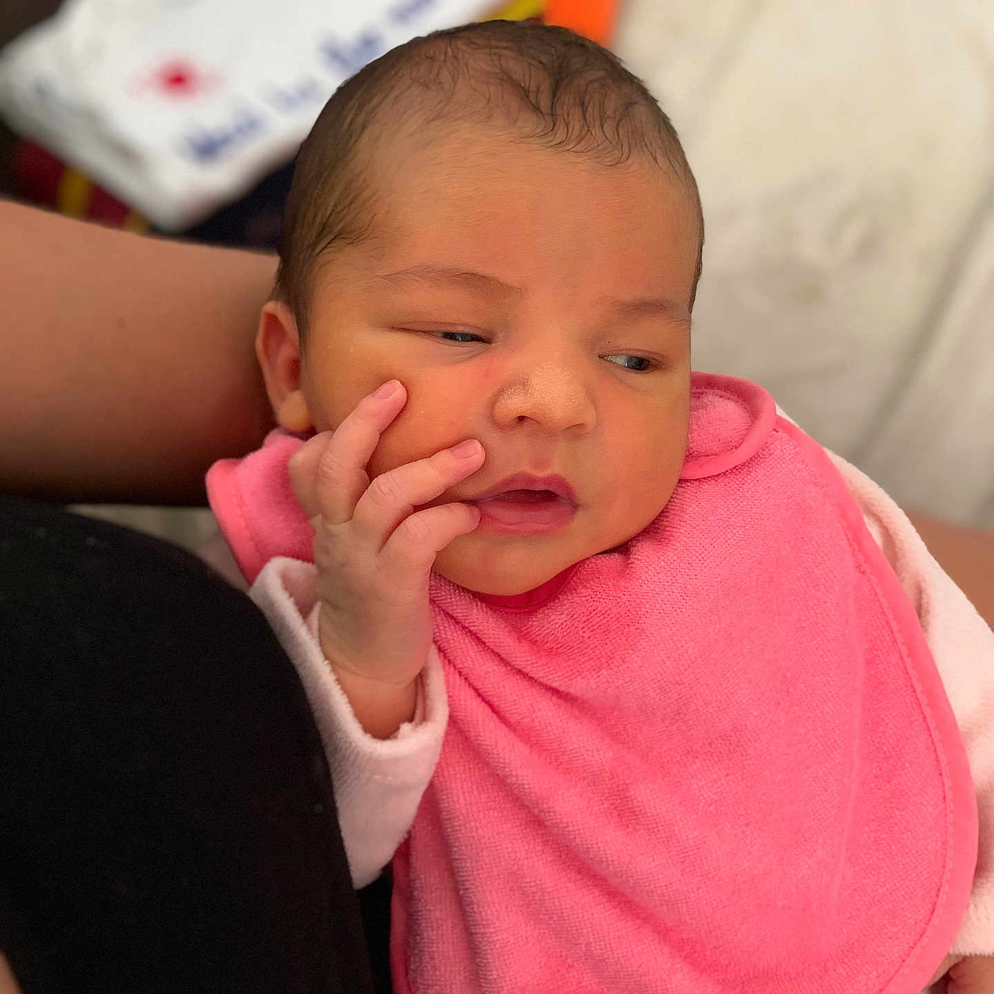 Anastasia participe au concours pour gagner de l'argent avec cette photo : baby, newborn, infant, pink_bib, hand, face, skin, clothing, person, portrait, resting, indoors, adult_arm, cute, small_hand, expression, young_child, soft_texture, warm, cozy