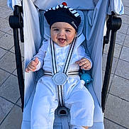 Gabriel participe au concours pour gagner de l'argent avec cette photo : baby, infant, stroller, harness, smiling, hat, bonnet, toy, outdoor, pavement, seat, happy, portrait, cute, clothing, socks, shoes, cheeks, hands, seatbelt