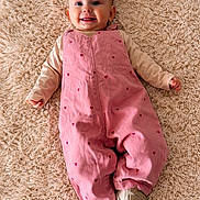 Léna a rejoint le concours — aidez-le/la à gagner de superbes lots ! baby, baby_fashion, carpet, child, clothing, cute, face, fluffy, happy, human, indoors, infant, lying_down, one_person, pink_overalls, portrait, small_child, smiling, toddler, white_shoes