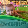 baby, infant, child, pool, water, foam_mat, floral_swimsuit, droplets, reflection, indoor_pool, toy, colorful, swimmer, face, eyes, smile, playtime, recreation, background_person, surface_texture