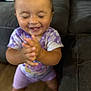 toddler, child, smiling, clapping, happy, indoor, purple_clothing, tie_dye, shorts, face, person, couch, furniture, wood_floor, baby, hands, cheerful, young_child, standing, casual