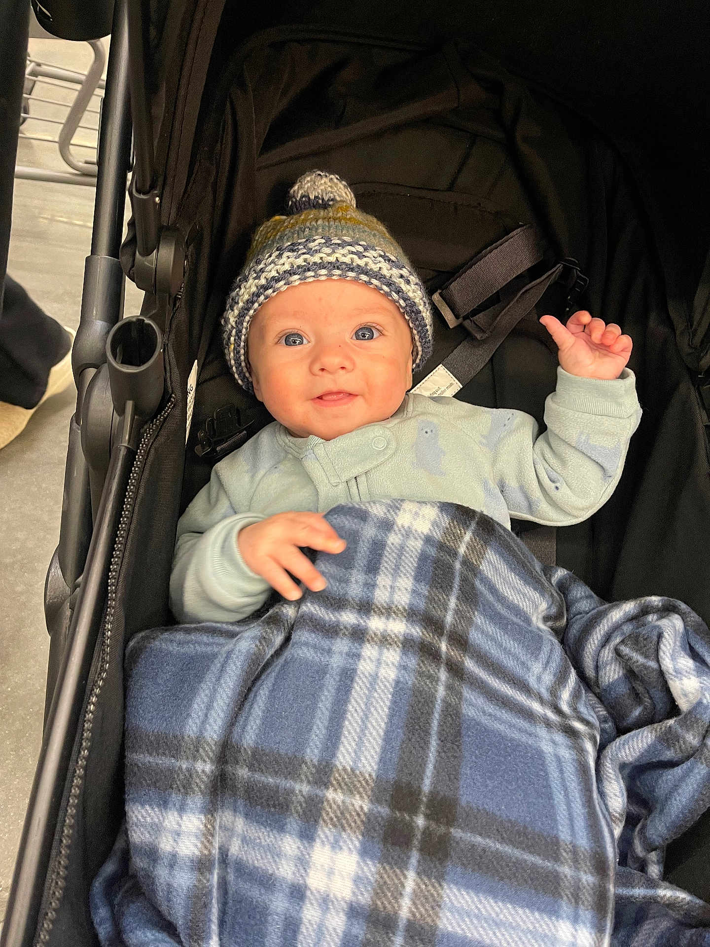 Bennett joined the competition — help win amazing prizes! baby, child, stroller, blanket, hat, knit_hat, plaid, blue, smile, face, person, clothing, baby_clothes, indoor, infant, cute, warm, cozy, hand, seatbelt