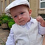 baby, child, white_clothing, vest, cap, blue_eyes, outdoor, building, hand, smartphone, person, expression, portrait, fashion, cute, serious, holding, adult_hand, garden, sidewalk