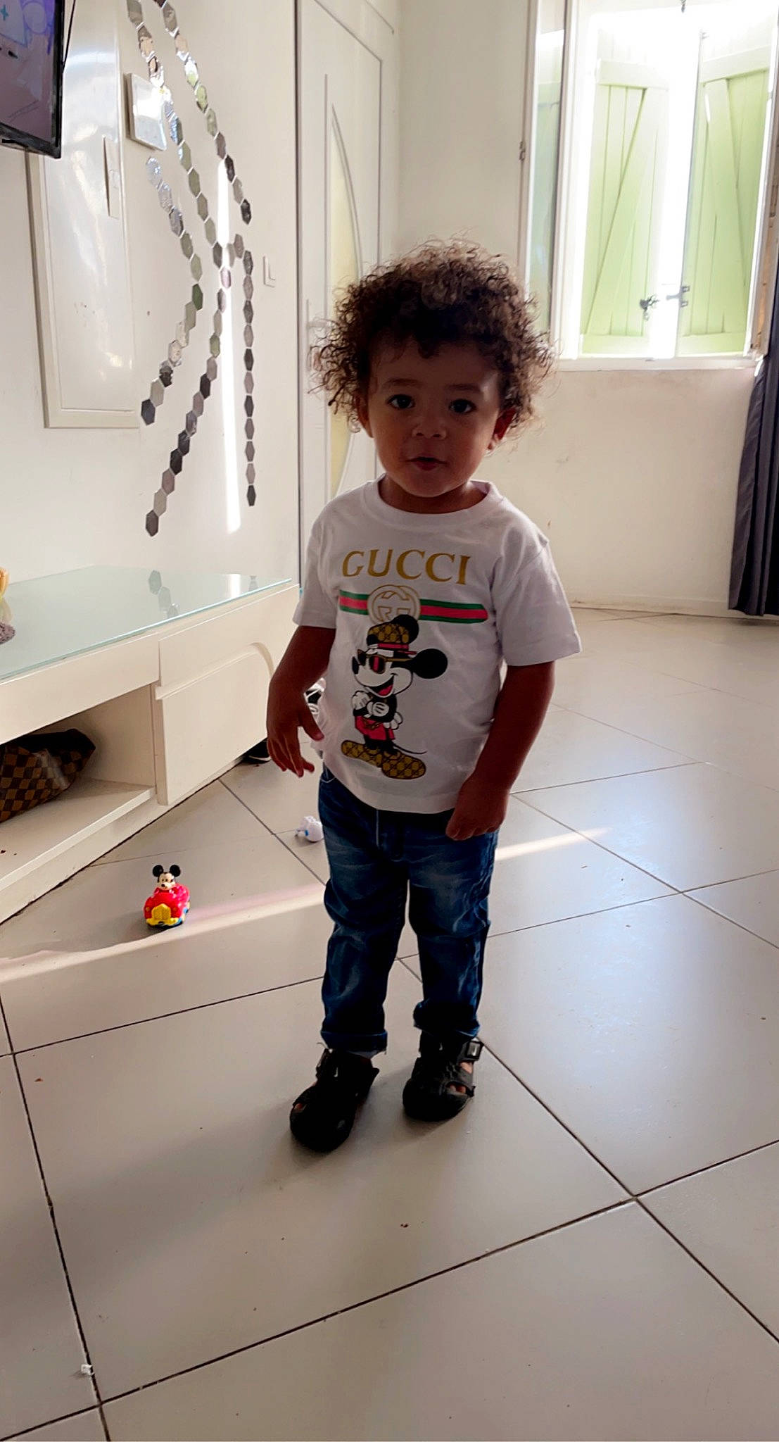 Haroun participe au concours pour gagner de l'argent avec cette photo : child, cleanliness, composite_material, curtain, denim, floor, flooring, fun, hardwood, jeans, joint, pattern, person, room, sleeve, standing, surprise, t_shirt, toddler, window