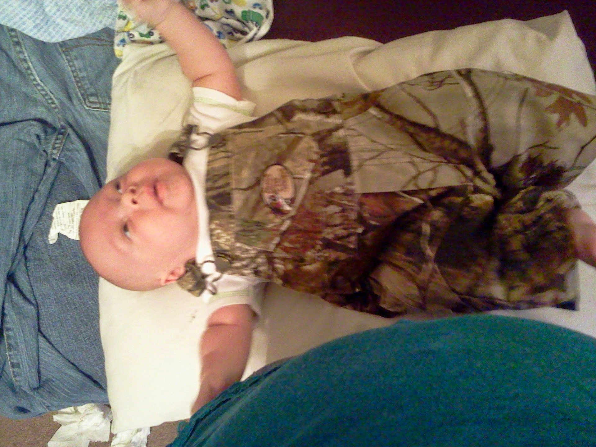 Braidon joined the competition — help win amazing prizes! baby, infant, pillow, clothing, camouflage, overalls, person, indoor, lying_down, white_shirt, denim, floor, carpet, fabric, casual, small_child, baby_face, arm, head, blanket