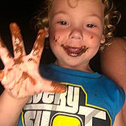 Braidon joined the competition — help win amazing prizes! child, toddler, chocolate, messy_face, hand, blue_shirt, curly_hair, smiling, portrait, happy, indoor, person, closeup, cute, fun, playful, food, face, skin, clothing