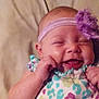 Zella is registered to the contest to win money with this photo: baby, child, smiling, headband, flower, colorful_clothing, infant, cute, happy, portrait, lying_down, soft_surface, skin, small_hands, closed_eyes, cheerful, toddler, playful, indoors, person