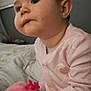 baby, child, infant, plush_toy, pink_clothing, onesie, indoor, bed, blanket, hand, face, cheeks, curious, cute, portrait, young_child, soft_toy, cuddly, seated, person