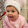 Maddison is registered to the contest to win money with this photo: baby, child, shopping_cart, hat, pink_clothing, tongue_out, cute, indoor, supermarket, person, infant, smiling, hands, face, apparel, winter_hat, pom_poms, shopping, grocery_store, young