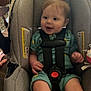 Luca joined the competition — help win amazing prizes! baby, car_seat, child, smiling, indoor, seatbelt, person, blue_clothing, hand, foot, pacifier, wooden_furniture, table, cushion, infant, happy, sitting, cute, face, room