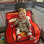 baby, child, pajamas, smile, red_chair, lightning_mcqueen, toy, playpen, indoor, car_themed_chair, foot, hand, face, happy, furniture, drawer, carpet, wood, person, home