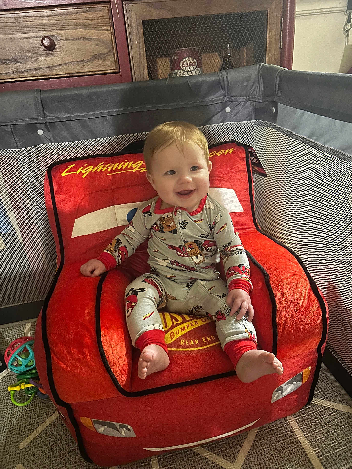 Luca joined the competition — help win amazing prizes! baby, child, pajamas, smile, red_chair, lightning_mcqueen, toy, playpen, indoor, car_themed_chair, foot, hand, face, happy, furniture, drawer, carpet, wood, person, home