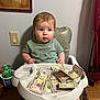 baby, toddler, high_chair, money, cash, can, sprite, shirt, cool_dude, foot, wood_floor, curtain, painting, wall, switch, cup_holder, face, person, indoor, expression