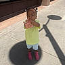 Aria joined the competition — help win amazing prizes! child, sidewalk, shadow, street_sign_shadow, boots, pink_boots, green_shirt, shorts, outdoor, sunny, building, concrete, person, hair_puffs, urban, daytime, standing, gesture, expression, casual_clothing
