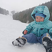 Gabrielle participe au concours pour gagner de l'argent avec cette photo : child, toddler, snow, winter_clothing, jacket, hat, boots, smiling, outdoor, ski_slope, forest, trees, snowy_ground, cold_weather, recreation, play, nature, hill, daytime, fun
