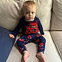 toddler, child, spiderman, pajamas, blue_clothing, red_clothing, sitting, couch, beige_couch, indoor, person, feet, expression, face, hair, blue_eyes, fabric, home, furniture, casual