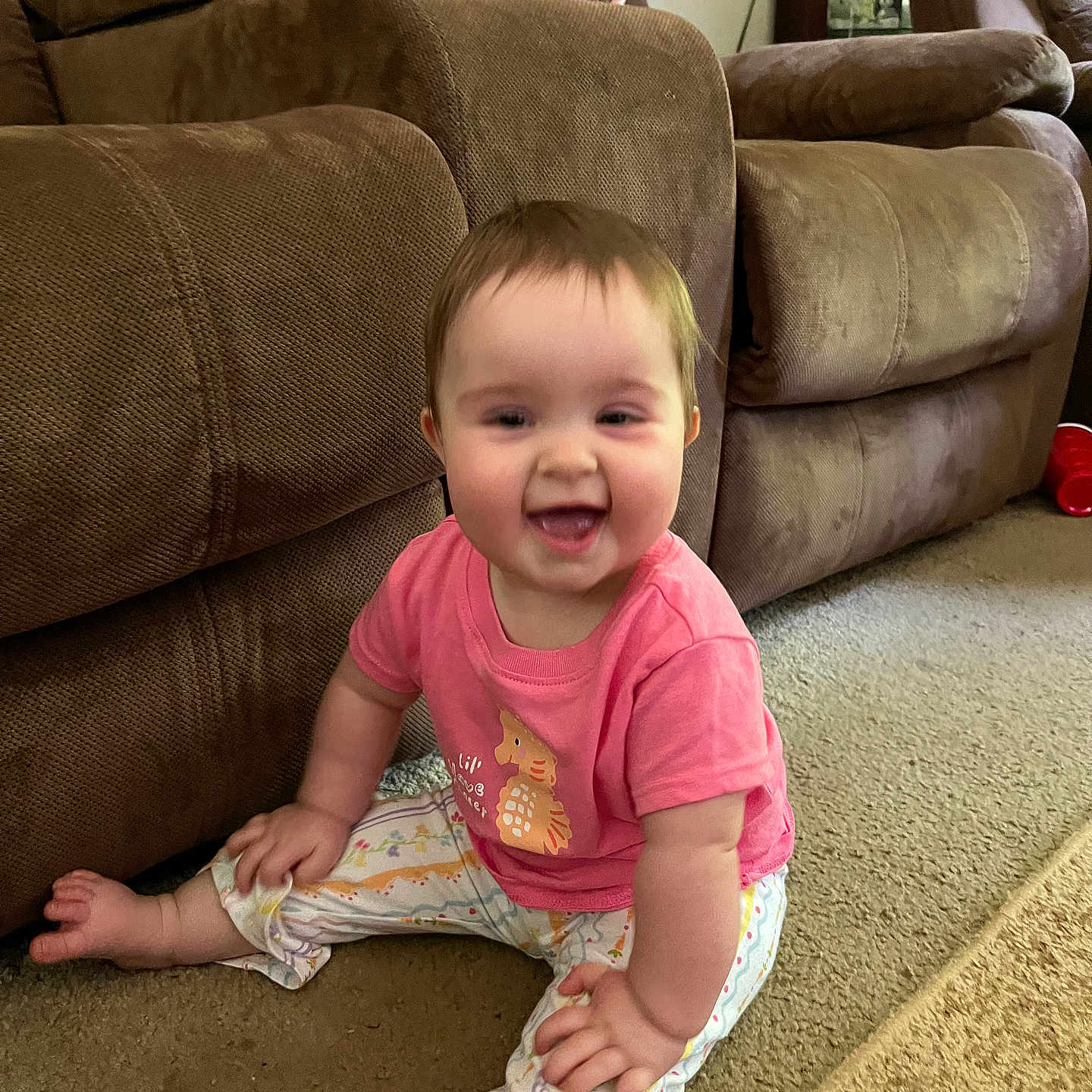 Lilia joined the competition — help win amazing prizes! baby, child, smiling, sitting, pink_shirt, patterned_pants, carpet, couch, furniture, indoor, living_room, happy, person, face, footwear_free, cute, young_child, home, playful, infant