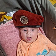 Joyce participe au concours pour gagner de l'argent avec cette photo : baby, badge, beret, blanket, car_seat, child, clothing, eyes, face, hat, indoor, infant, metal_emblem, onesie, pacifier_clip, pink_towel, plush_toy, portrait, surprised, tongue_out