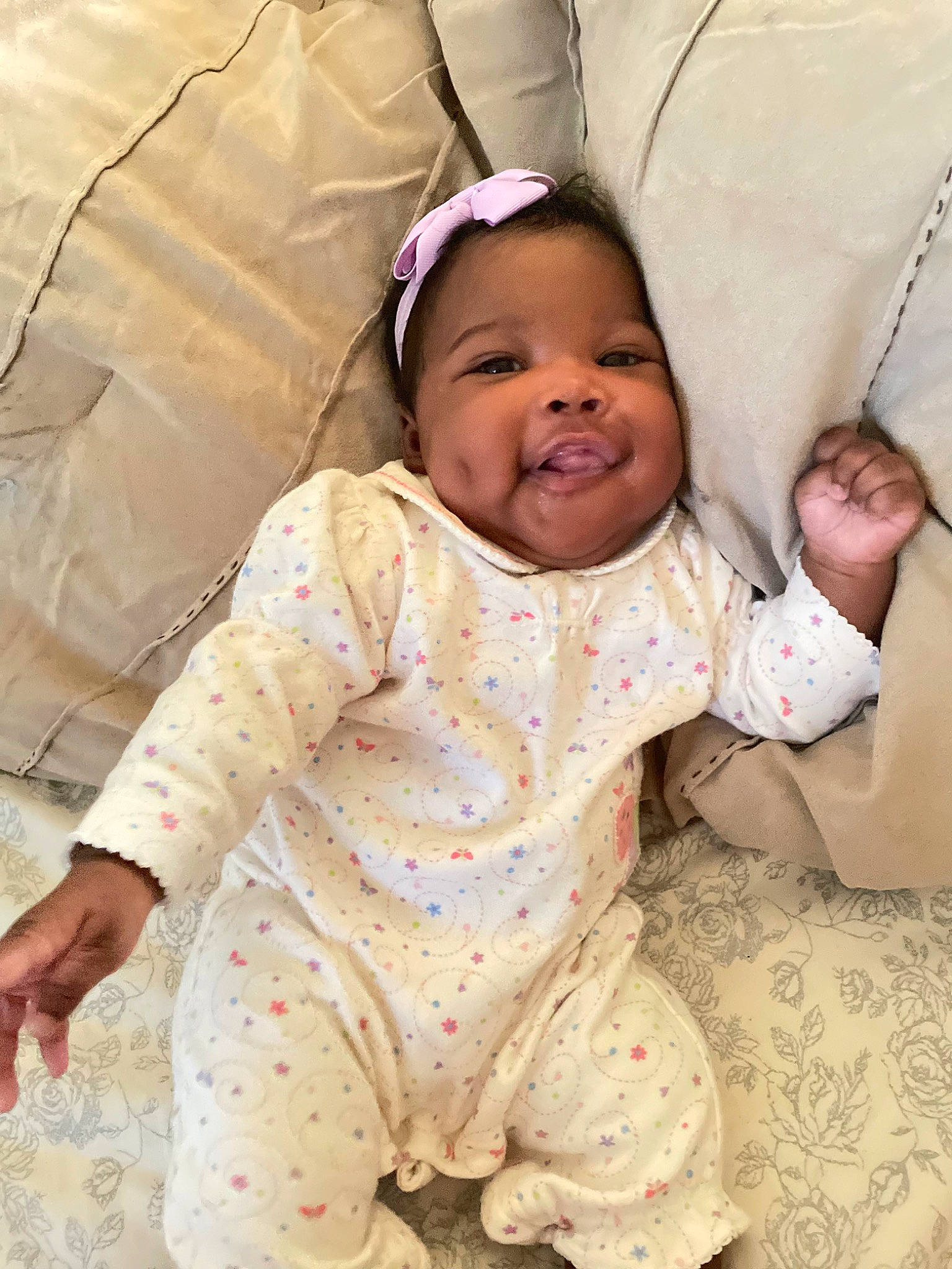 Ariel is registered to the contest to win money with this photo: baby, baby_toddler_clothing, cheek, child, comfort, flooring, fun, happy, head, linens, mouth, neck, nose, pattern, person, sitting, skin, sleeve, smile, textile