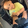 Amaro is registered to the contest to win money with this photo: baby, black_socks, car_interior, car_seat, child, clothing, curly_hair, happy, indoors, person, portrait, safety, seat, seatbelt, sitting, smiling, toddler, window, yellow_shirt, young_child