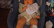 Iayla is registered to the contest to win money with this photo: baby, car_seat, bow, bib, couch, leather, footwear, baby_clothing, infant, indoor, child, person, seat, toy, bottle, floor, relaxing, cute, portrait, small