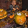 baby, child, halloween, pumpkin, jackolantern, carved_pumpkin, autumn_leaves, costume, smile, face, orange, black_clothing, headband, festive, celebration, decoration, indoor, holiday, cute, happy