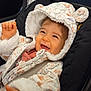 baby, child, smiling, hood, jacket, car_seat, cute, happy, clothing, infant, seatbelt, indoor, person, face, expression, warm_clothing, fur_trim, joy, small_hands, transportation