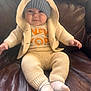 Ava Angeline is registered to the contest to win money with this photo: baby, infant, child, knitwear, hood, bear_ears, blue_hat, socks, sitting, leather_couch, cozy, cute, clothing, portrait, smile, indoor, soft_lighting, warm_colors, cute_expression, comfortable