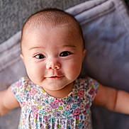 Ava Angeline joined the competition — help win amazing prizes! baby, infant, face, smile, eyes, arms, floral_dress, blanket, soft, cute, child, portrait, closeup, happy, skin, head, person, young, indoors, laying