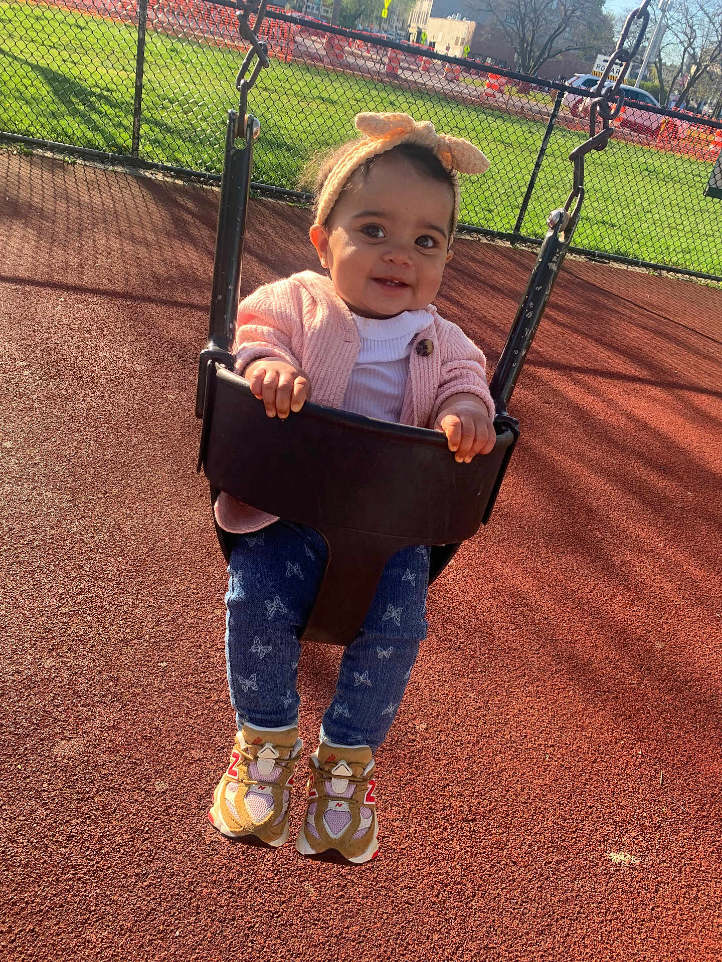Kazora joined the competition — help win amazing prizes! child, toddler, swing, playground, headband, bow, pink_cardigan, jeans, butterfly_print, sneakers, outdoor, sunny, smiling, happy, chain_link_fence, grass, play_area, baby, fun, daytime