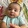 Dylan joined the competition — help win amazing prizes! baby, infant, face, hands, clothing, striped_onesie, quilt, floral_pattern, cheeks, skin, eyes, mouth, portrait, lying_down, cute, child, closeup, expression, hand_pose, indoors