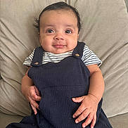 Dylan joined the competition — help win amazing prizes! baby, infant, child, smile, face, eyes, hands, clothing, striped_shirt, overalls, cushion, beige, indoor, portrait, cute, young_child, sitting, soft_texture, comfortable, happy