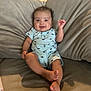 Dylan is registered to the contest to win money with this photo: baby, infant, couch, smile, happy, face, onesie, clothing, indoor, furniture, feet, legs, child, person, home, curly_hair, skin, relaxing, seated, cute