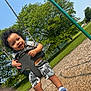 Jovani joined the competition — help win amazing prizes! toddler, swing, playground, smiling, child, outdoor, park, happy, curly_hair, grass, tree, blue_sky, clothing, shorts, socks, daylight, metal_chain, wood_chips, greenery, fun