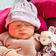 Freya participe au concours pour gagner de l'argent avec cette photo : baby, newborn, sleeping, infant, beanie, knit_sweater, plush_toy, stuffed_animal, pink_pillow, blanket, closeup, portrait, indoors, cozy, hand, cheeks, closed_eyes, lips, soft_toys, cuteness