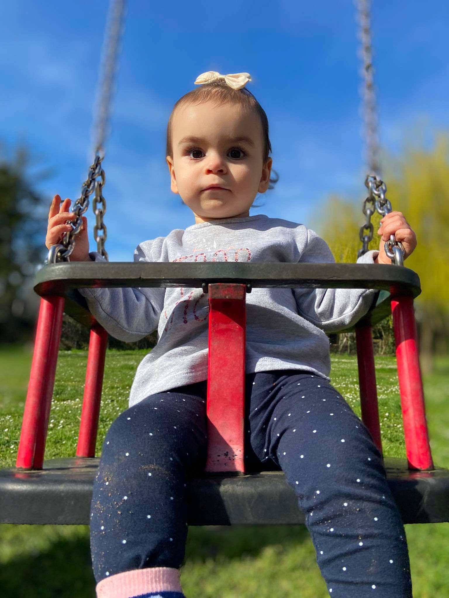 Myla participe au concours pour gagner de l'argent avec cette photo : baby_toddler_clothing, child, city, cloud, electric_blue, fun, grass, happy, leisure, outdoor_play_equipment, person, play, playground, recreation, sitting, sky, sleeve, swing, toddler, vacation