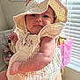 Everly is registered to the contest to win money with this photo: baby, child, hat, clothing, arm, person, indoor, window, light, expression, cute, infant, skin, face, hand, textile, tattoo, blinds, background, room