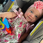 Ceceila joined the competition — help win amazing prizes! baby, child, car_seat, pink_dress, headband, flower, toy, smile, blue_eyes, rosy_cheeks, infant, cute, happy, seated, colorful, plastic_rings, fabric, pattern, ribbon, portrait