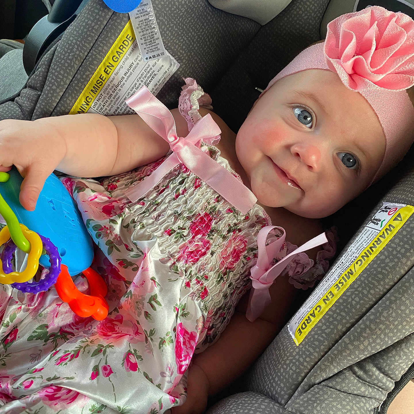Ceceila joined the competition — help win amazing prizes! baby, child, car_seat, pink_dress, headband, flower, toy, smile, blue_eyes, rosy_cheeks, infant, cute, happy, seated, colorful, plastic_rings, fabric, pattern, ribbon, portrait