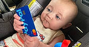 Ceceila joined the competition — help win amazing prizes! baby, infant, child, car_seat, vehicle, portrait, face, eyes, curious, sitting, clothing, knitwear, blanket, toy, colorful, blue_card, mastercard, indoor, travel, safe