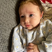 émie participe au concours pour gagner de l'argent avec cette photo : baby, infant, child, face, hand, clothing, sweater, ponytail, daisy_pattern, blanket, texture, soft, cute, portrait, indoors, skin, expression, lying_down, young, cozy