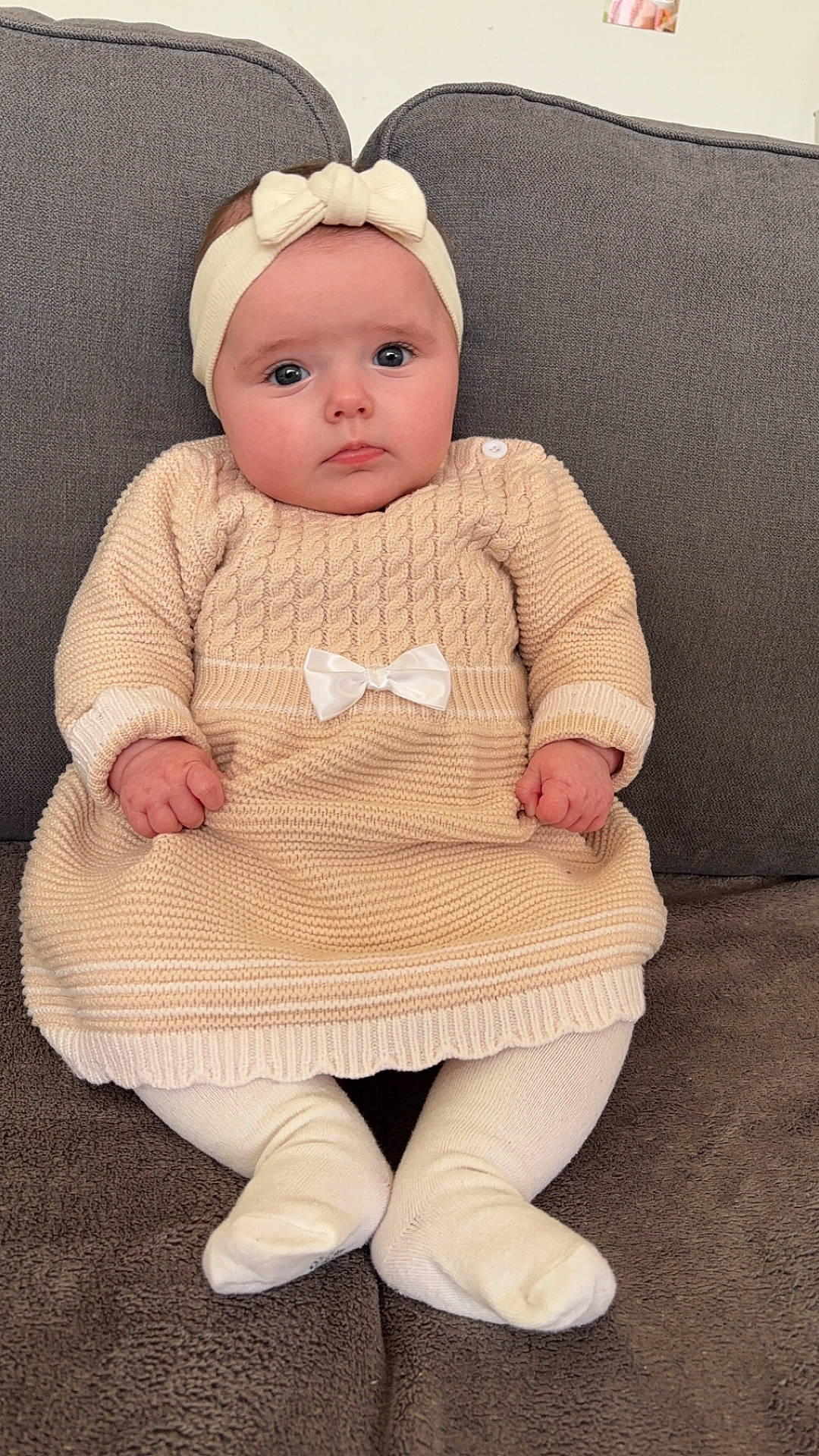 baby, beanie, bonnet, cap, clothing, couch, face, furniture, hat, head, hosiery, knitwear, newborn, pants, person, photography, portrait, sitting, sock, sweater