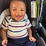 baby, child, smiling, car_seat, striped_shirt, navy_pants, infant, happy, cute, seat_belt, indoor, person, child_seat, clothing, sitting, face, head, skin, hands, footwear