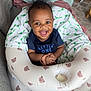 baby, infant, smiling, happy, child, indoor, inflatable_ring, bear_pattern, clothing, blue_shirt, wild_hair, person, cute, seated, toddler, blanket, fabric, home, playful, joyful