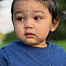 child, toddler, portrait, face, person, blue_shirt, outdoor, close_up, looking_away, curious, serious, young, head, hair, eyes, nose, mouth, blurred_background, daylight, photography