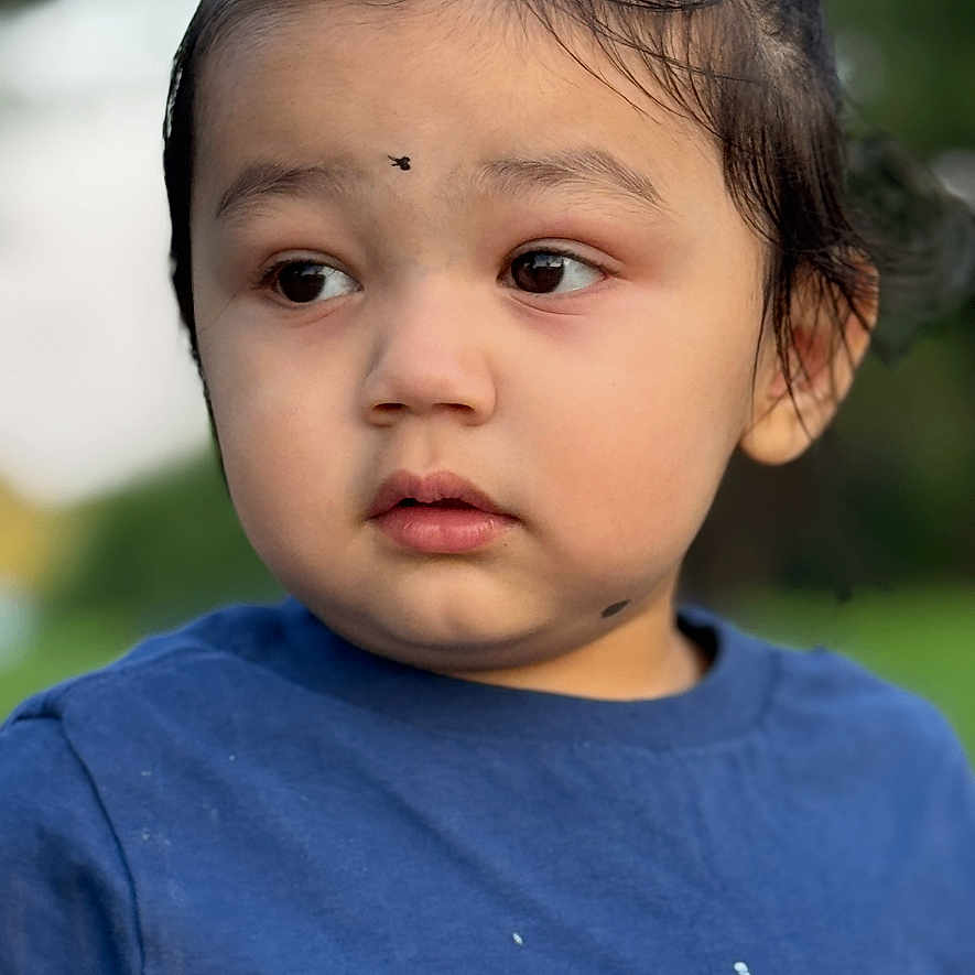 Arshan is registered to the contest to win money with this photo: child, toddler, portrait, face, person, blue_shirt, outdoor, close_up, looking_away, curious, serious, young, head, hair, eyes, nose, mouth, blurred_background, daylight, photography