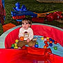 Ezequiel Cortinez is registered to the contest to win money with this photo: toddler, child, ball_pit, playground, outdoor, balls, slide, grass, evening, toy, play_equipment, person, clothing, cute, curious, sitting, colorful, recreation, young_child, fun