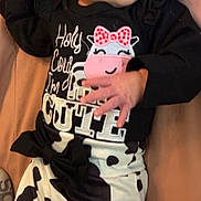 Gianna is registered to the contest to win money with this photo: baby, infant, child, cow_print, headband, black_and_white, clothing, cute, sleeping, lying_down, hand, face, apparel, soft_surface, pink_background, newborn, adorable, resting, person, toddler